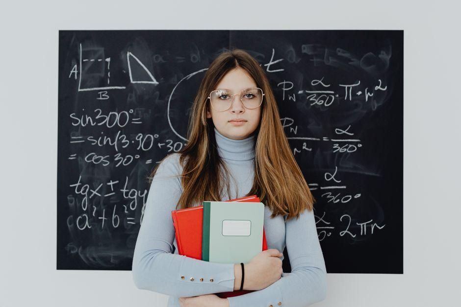 Élève devant un tableau de mathématiques avec ses cahiers